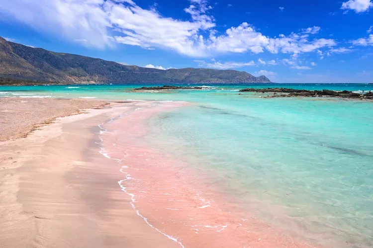 Vibrant pink sands meeting clear turquoise waves at Elafonisi Beach in Crete