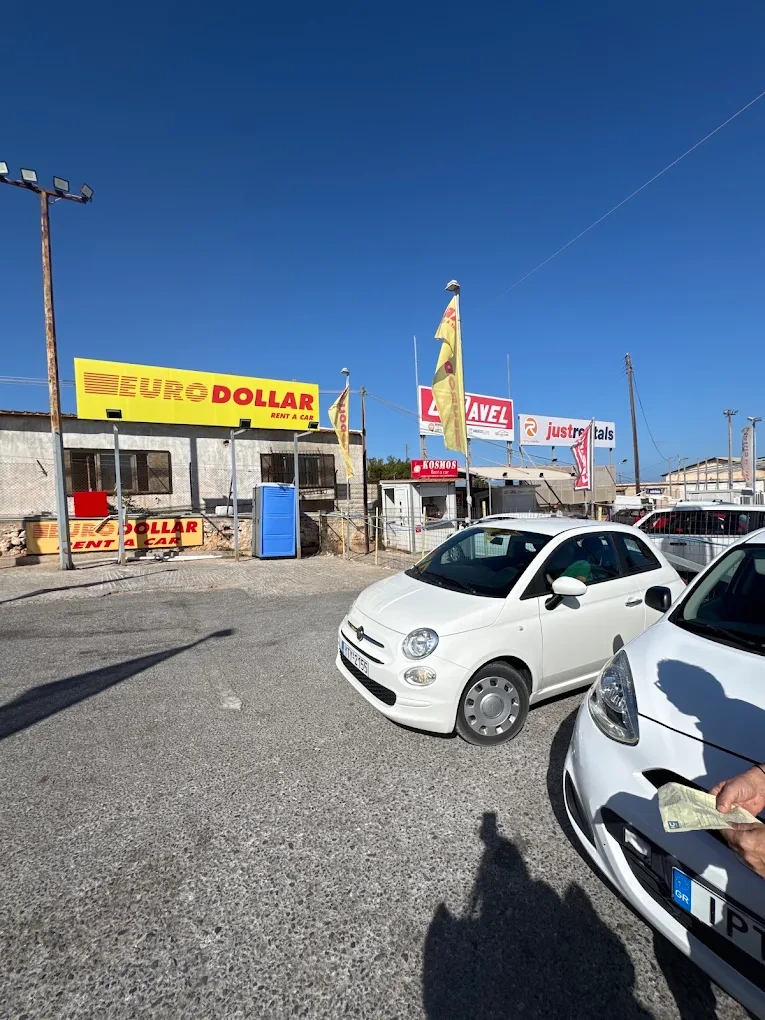 A modern rental car parked on a hillside highway overlooking the beautiful coastline of Crete