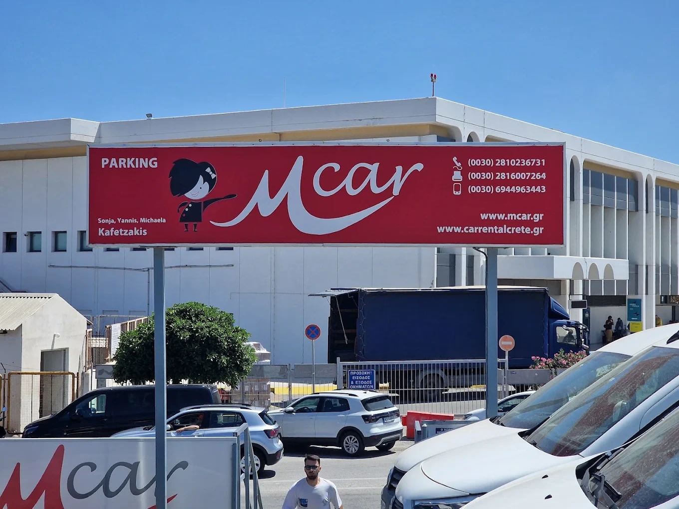 A modern rental car parked on a hillside highway overlooking the beautiful coastline of Crete