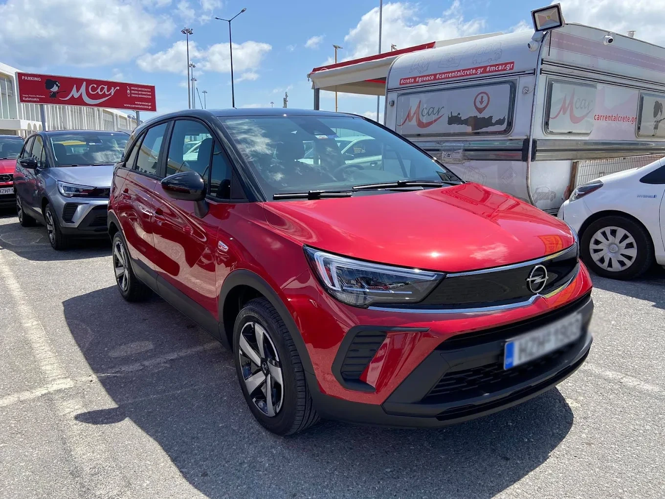 A modern rental car parked on a hillside highway overlooking the beautiful coastline of Crete