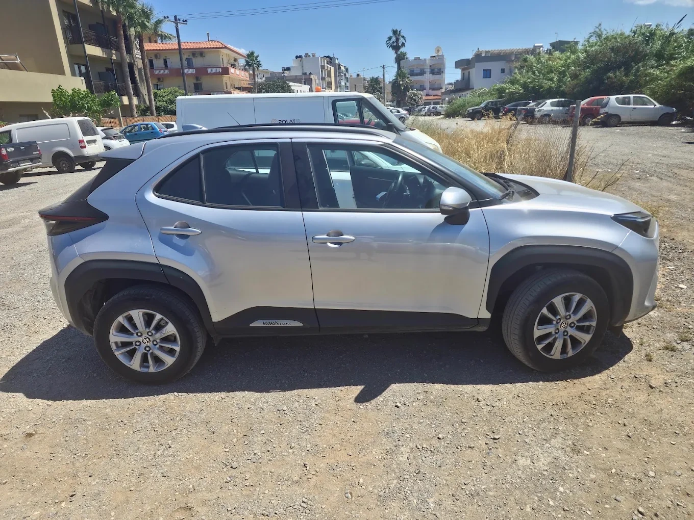 A modern rental car parked on a hillside highway overlooking the beautiful coastline of Crete
