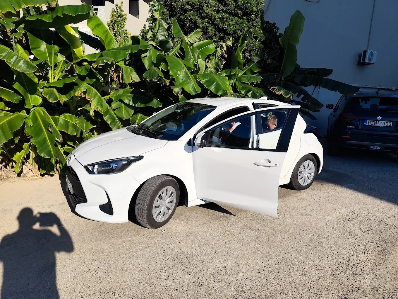 A modern rental car parked on a hillside highway overlooking the beautiful coastline of Crete